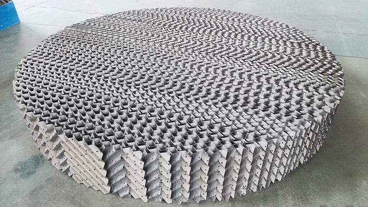 Workers installing perforated plate structured packing modules inside a distillation column