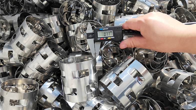 Workers loading stainless steel Pall Rings into a distillation column during turnaround